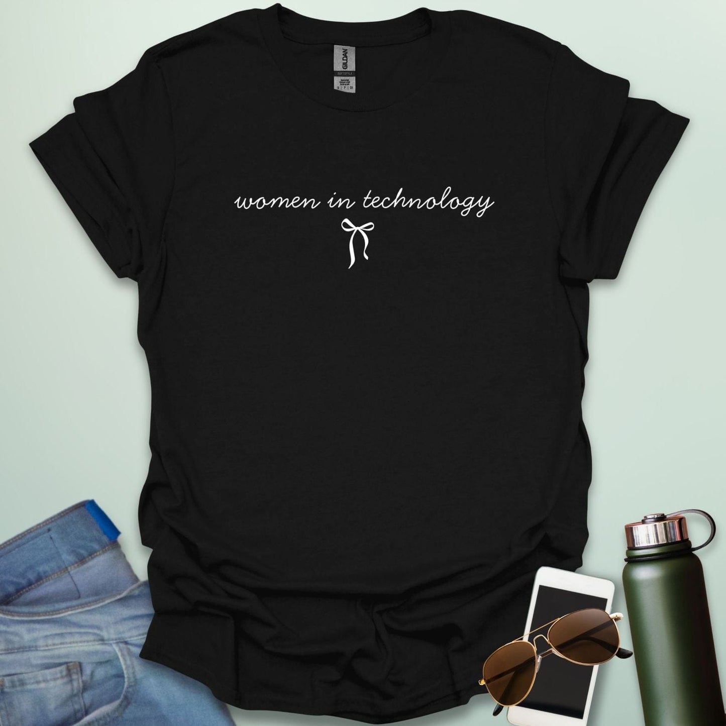 A black t-shirt with the phrase 'women in technology' in an elegant cursive font, with a small bow underneath.
