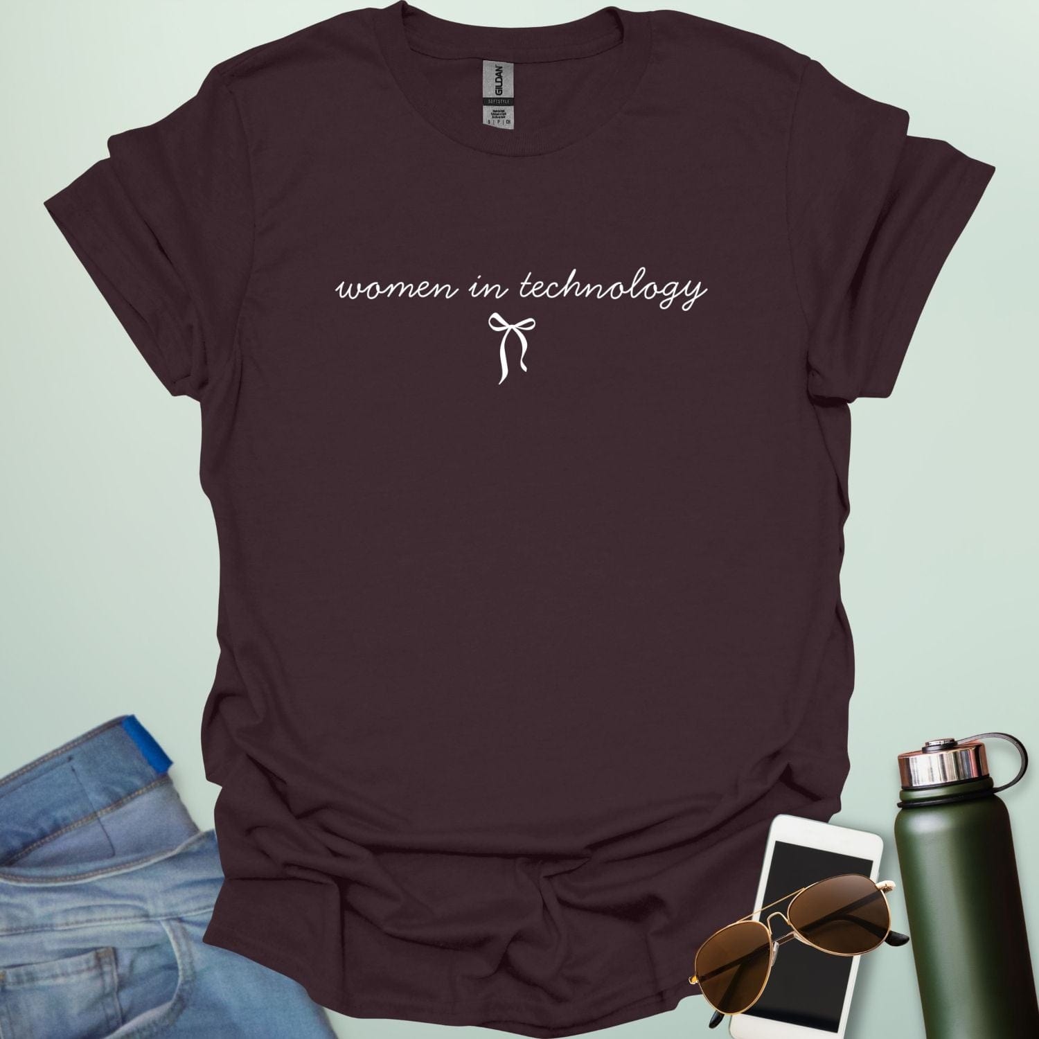 A dark chocolate t-shirt with the phrase 'women in technology' in an elegant cursive font, with a small bow underneath.