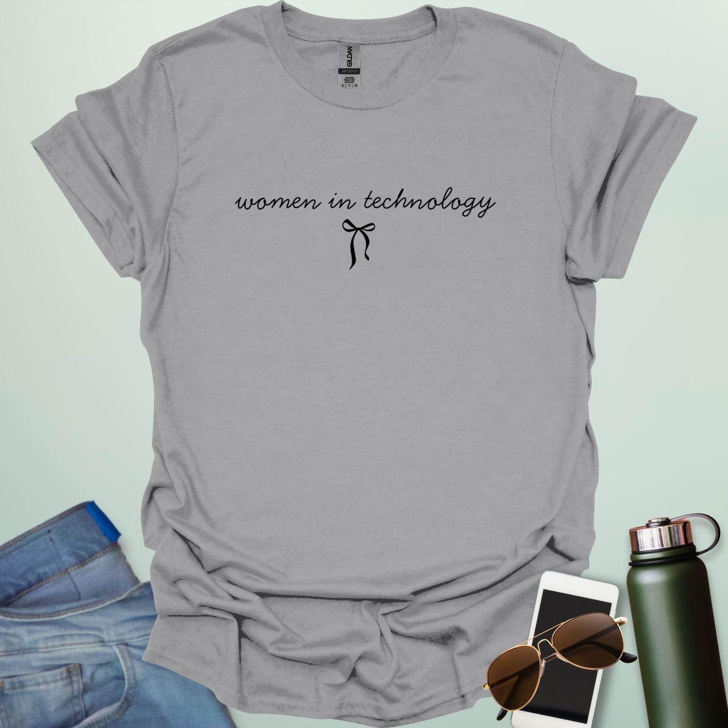 A sport grey t-shirt with the phrase 'women in technology' in an elegant cursive font, with a small bow underneath.