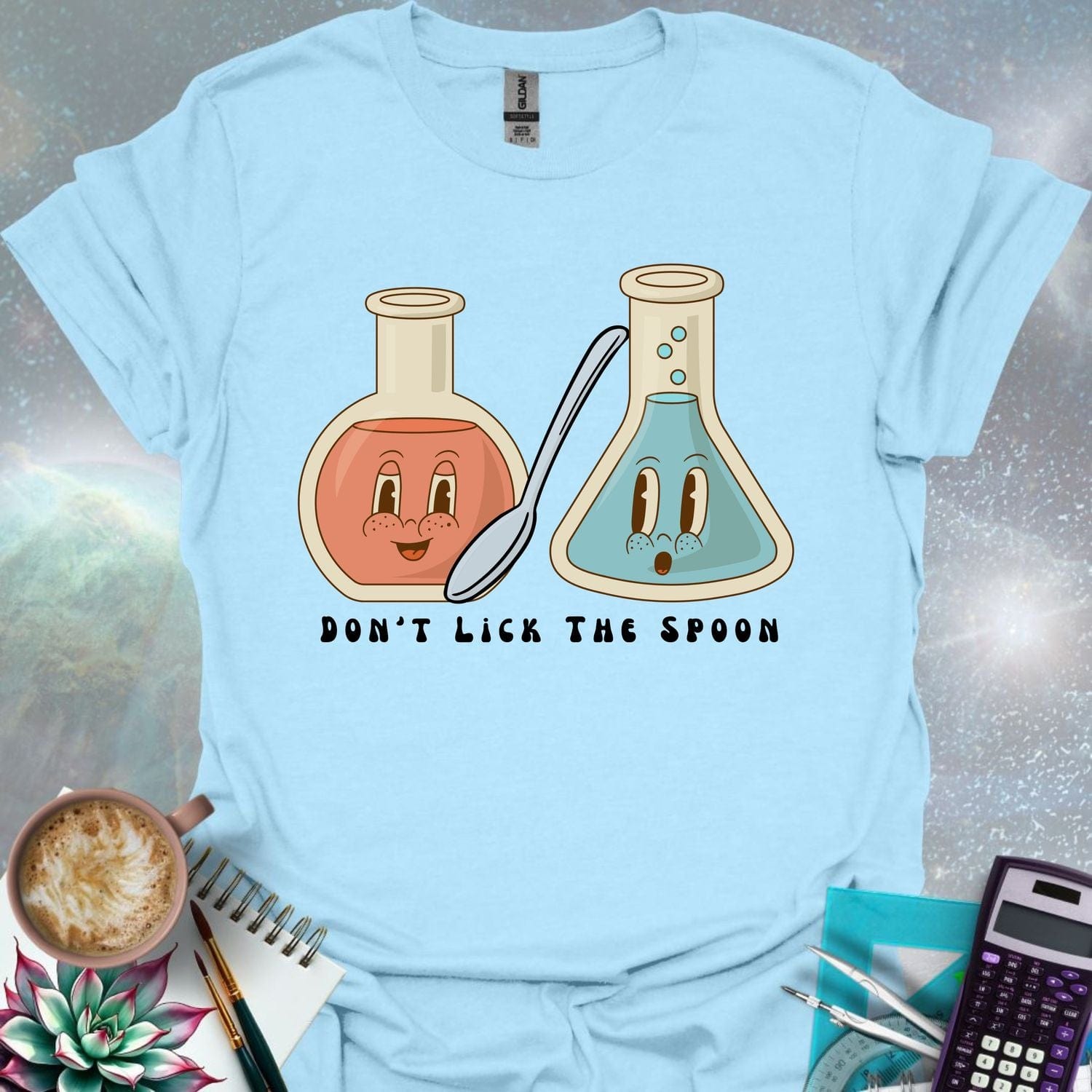 T-shirt design featuring two cartoonish retro beakers, one smiling, one surprised, with a spoon and the text 'Don't Lick The Spoon'.
