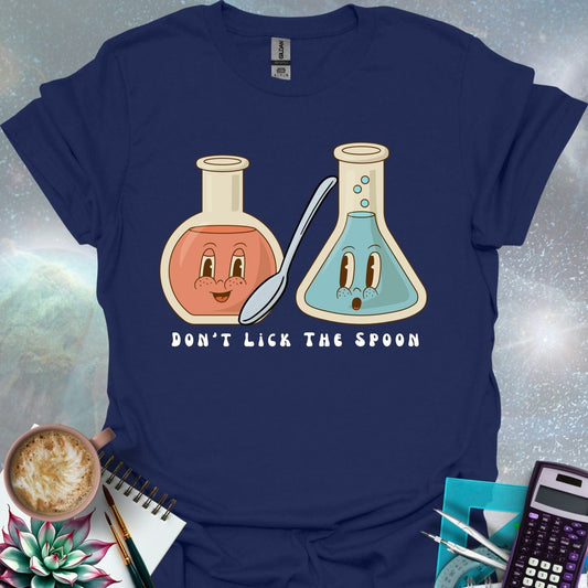 T-shirt design featuring two cartoonish retro beakers, one smiling, one surprised, with a spoon and the text 'Don't Lick The Spoon'.