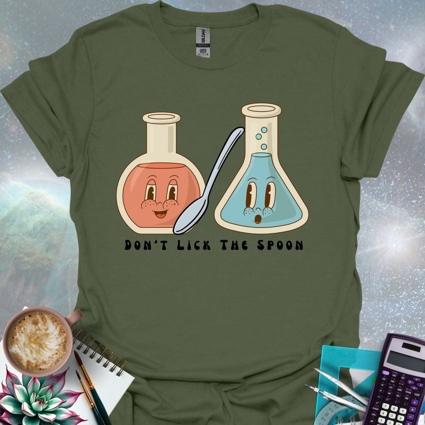 T-shirt design featuring two cartoonish retro beakers, one smiling, one surprised, with a spoon and the text 'Don't Lick The Spoon'.