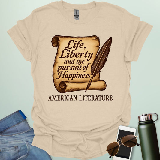 A tan t-shirt with a vintage-style scroll and quill pen, and the text 'Life, Liberty and the pursuit of Happiness' and 'American Literature.'