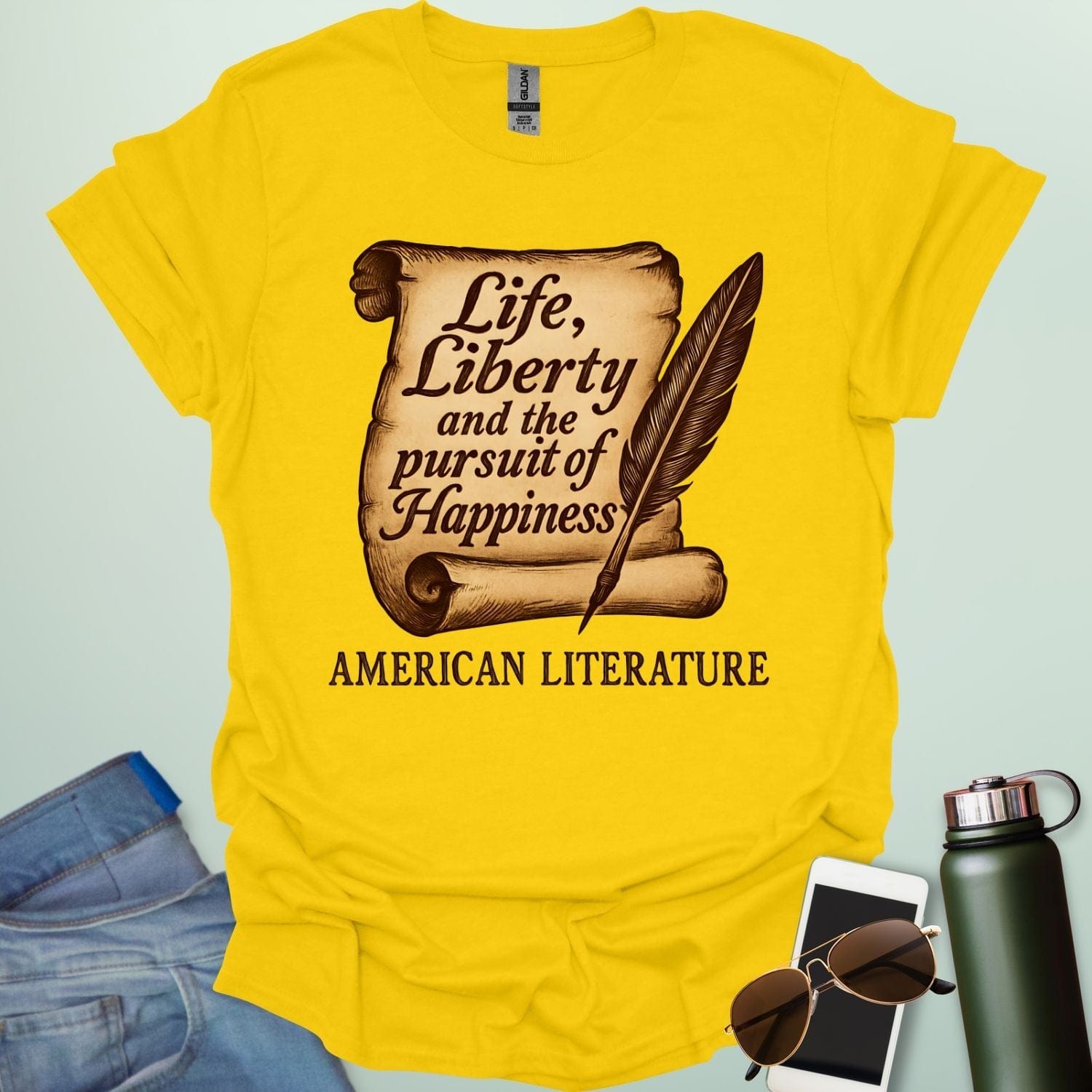 A daisy color t-shirt with a vintage-style scroll and quill pen, and the text 'Life, Liberty and the pursuit of Happiness' and 'American Literature.'