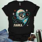 Laika First Dog in Space t-shirt with retro Soviet cosmonaut design featuring Laika in a helmet and rocket ship illustration.