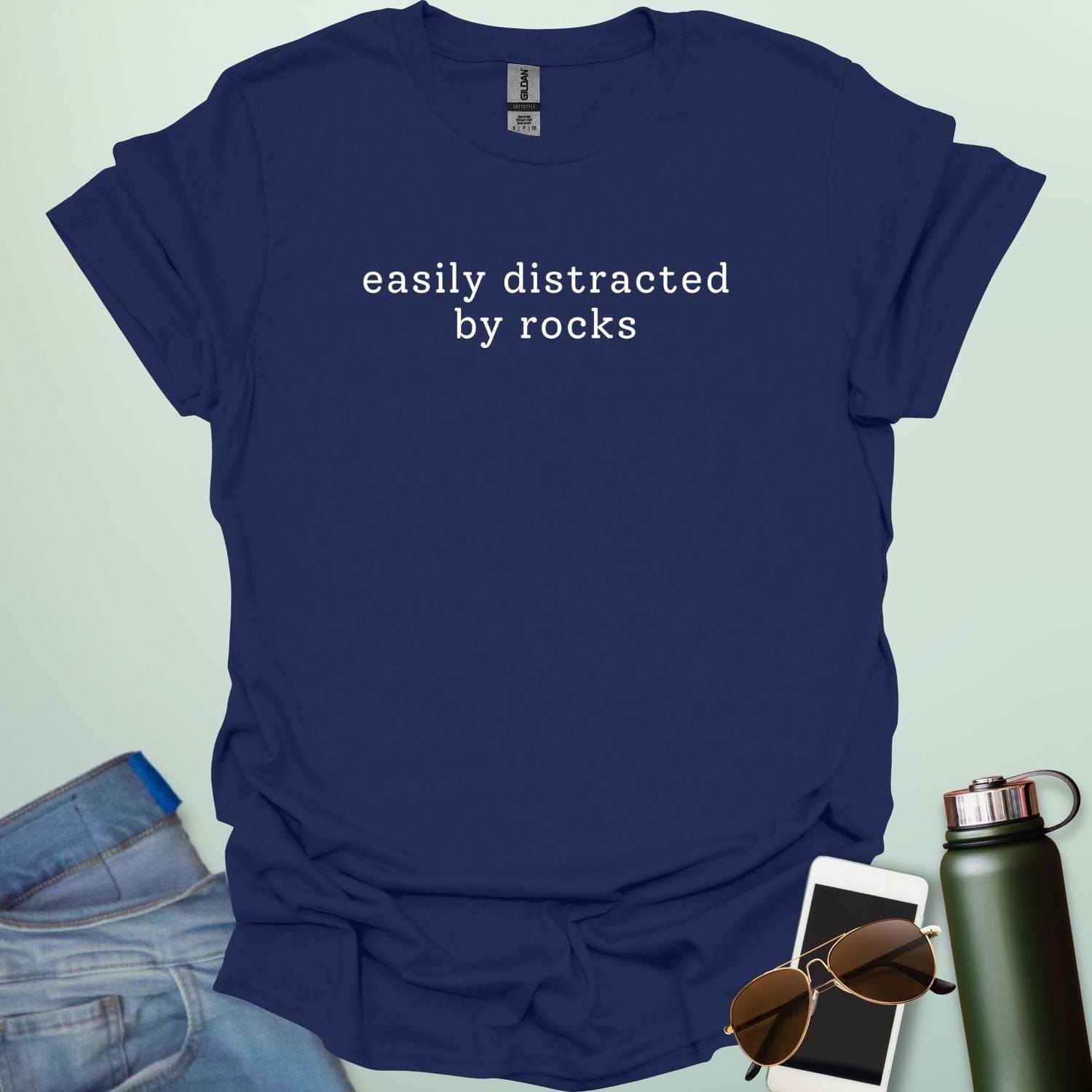 EASYLY DISTRACTED BY ROCKS t-shirt with distressed uppercase typography and small rock icons beside ‘BY’ — minimalist geology humor tee.