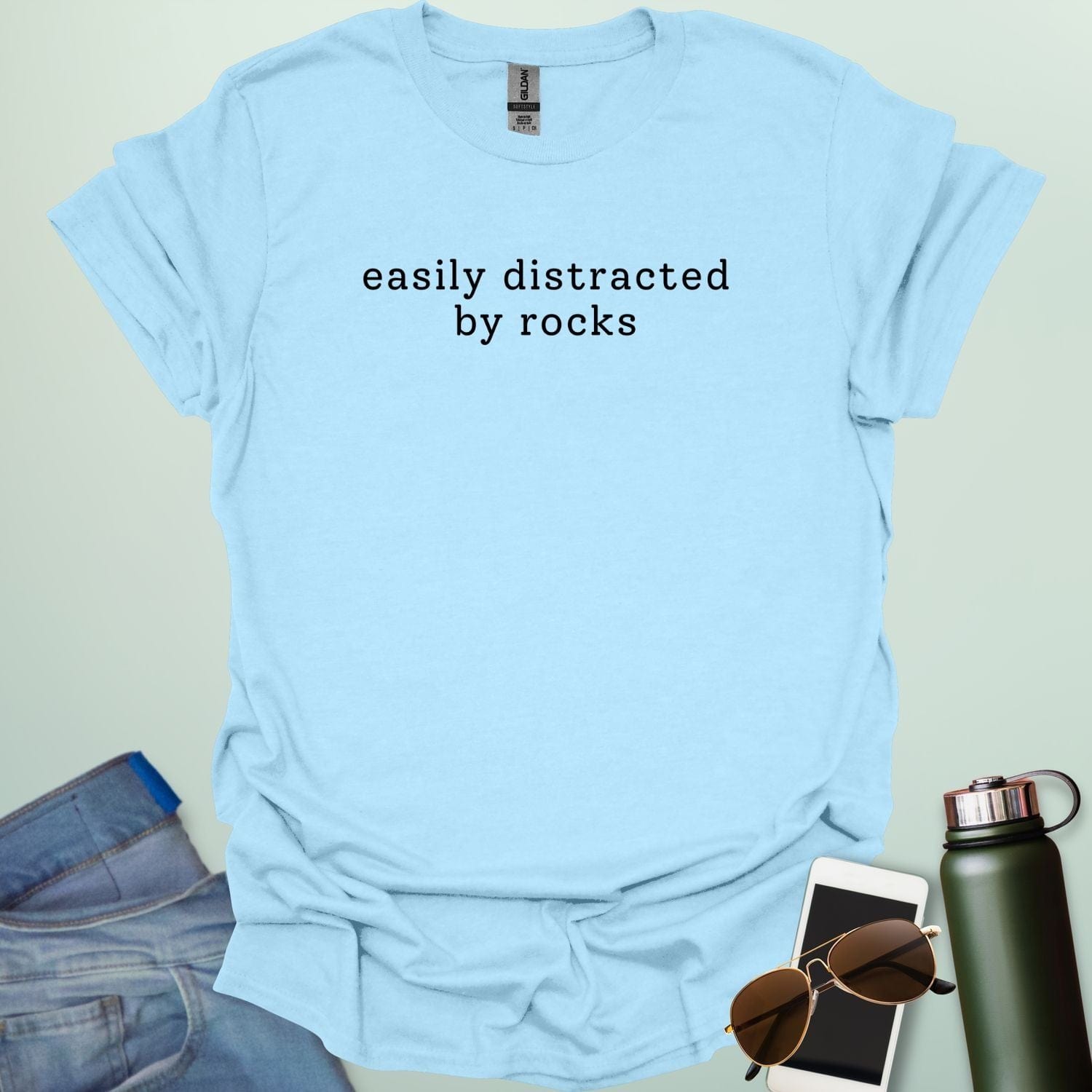 EASYLY DISTRACTED BY ROCKS t-shirt with distressed uppercase typography and small rock icons beside ‘BY’ — minimalist geology humor tee.