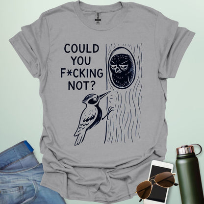 Minimal illustration of an irritated owl peeking from its tree burrow while a woodpecker pecks at the trunk, with bold text reading “COULD YOU F*CKING NOT?” on a dark background.