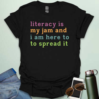 Black T-shirt with the text 'literacy is my jam and i'm here to spread it' in colorful, bold lettering.