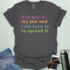 Charcoal gray T-shirt with the text 'literacy is my jam and i'm here to spread it' in colorful, bold lettering.
