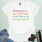 White T-shirt with the text 'literacy is my jam and i'm here to spread it' in colorful, bold lettering.