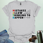 An ice grey t-shirt with the text 'MISTAKES ALLOW THINKING TO HAPPEN,' with the first letter of each word forming 'MATH' vertically, and a ruler and math symbols.