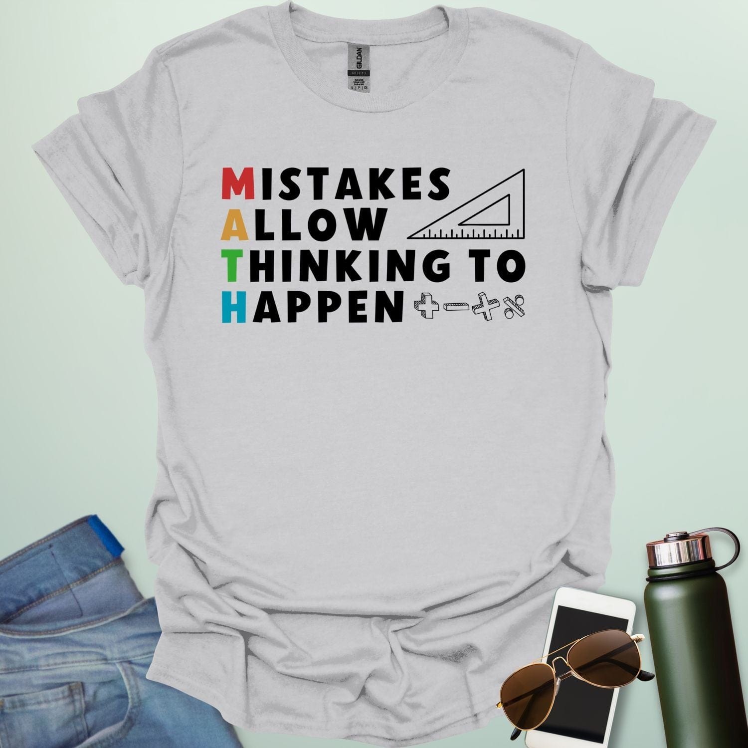 An ice grey t-shirt with the text 'MISTAKES ALLOW THINKING TO HAPPEN,' with the first letter of each word forming 'MATH' vertically, and a ruler and math symbols.