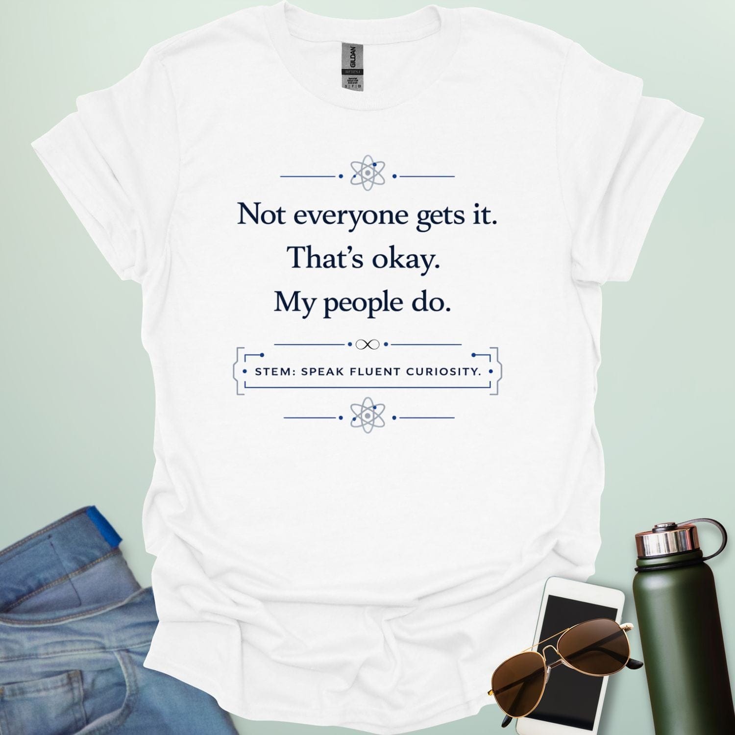 T-shirt with navy blue text reading 'Not everyone gets it. That's okay. My people do.' and 'STEM: SPEAK FLUENT CURIOSITY' with atom icons."