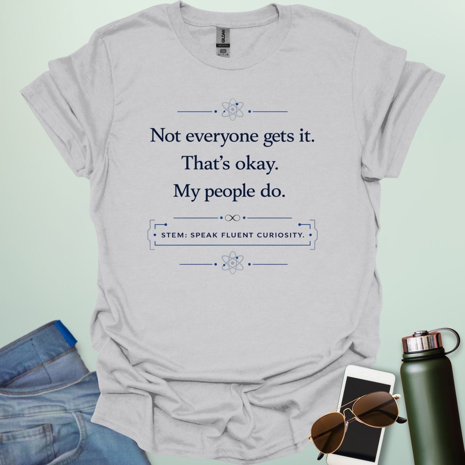 T-shirt with navy blue text reading 'Not everyone gets it. That's okay. My people do.' and 'STEM: SPEAK FLUENT CURIOSITY' with atom icons."