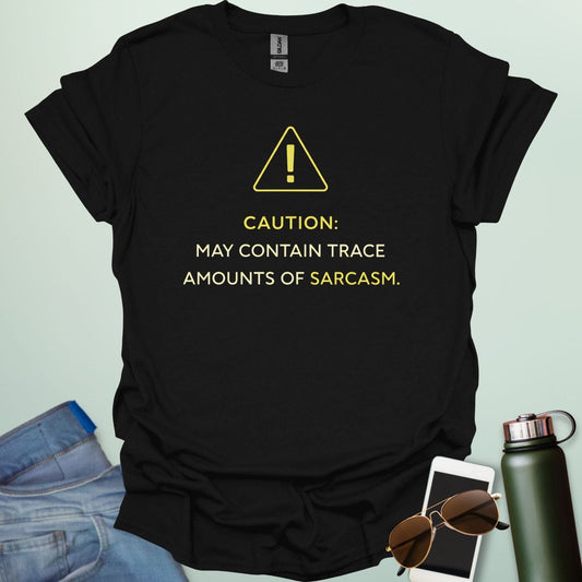 A minimalist science-themed design featuring a warning triangle with an "!" in the center with text "CAUTION: MAY CONTAIN TRACE AMOUNTS OF SARCASM" underneath.