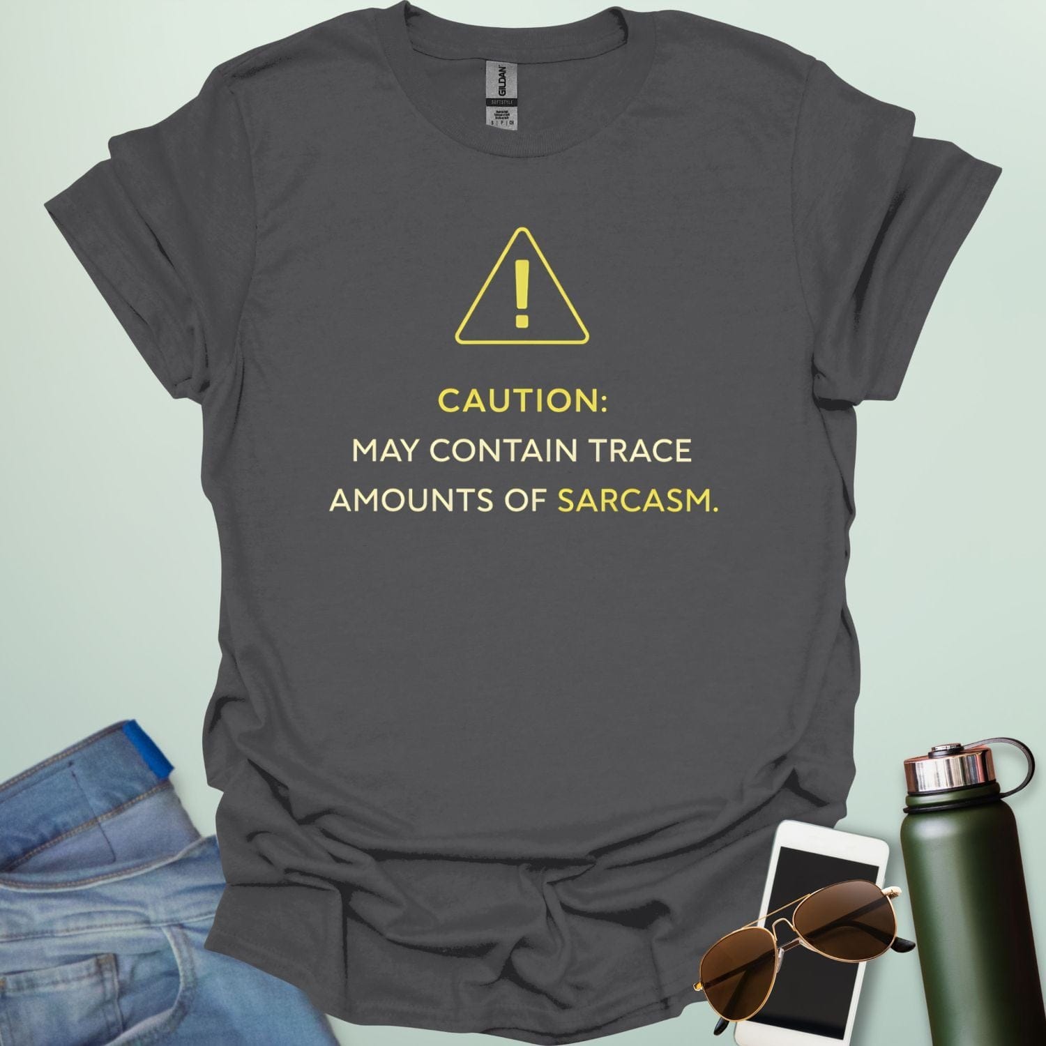 A minimalist science-themed design featuring a warning triangle with an "!" in the center with text "CAUTION: MAY CONTAIN TRACE AMOUNTS OF SARCASM" underneath.