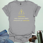 A minimalist science-themed design featuring a warning triangle with an "!" in the center with text "CAUTION: MAY CONTAIN TRACE AMOUNTS OF SARCASM" underneath.