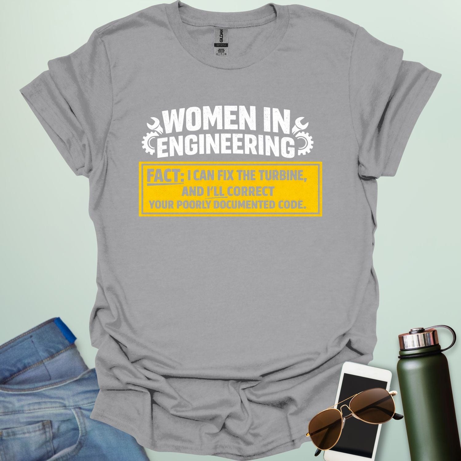 Graphic design featuring the text 'WOMEN IN ENGINEERING' with wrench and gear icons above a yellow box reading 'FACT: I CAN FIX THE TURBINE, AND I’LL CORRECT YOUR POORLY DOCUMENTED CODE.'