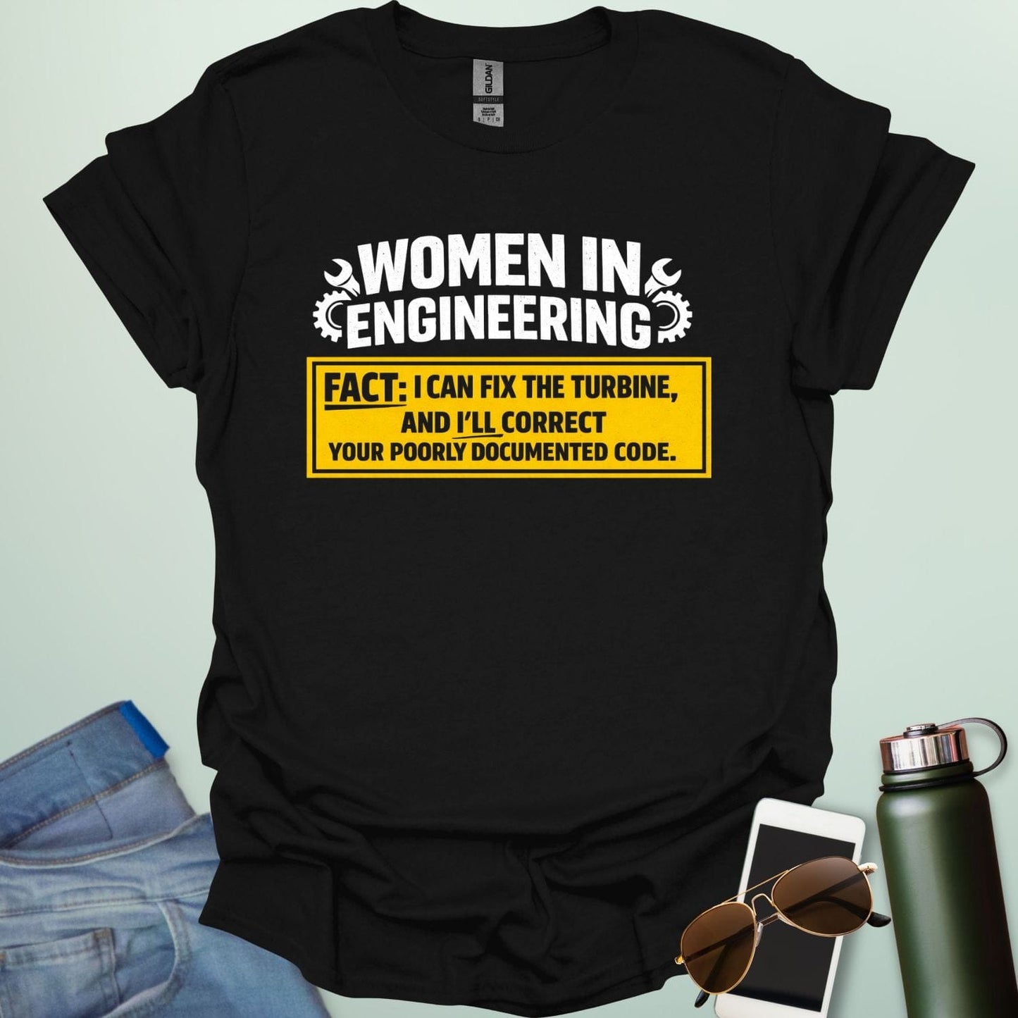 Graphic design featuring the text 'WOMEN IN ENGINEERING' with wrench and gear icons above a yellow box reading 'FACT: I CAN FIX THE TURBINE, AND I’LL CORRECT YOUR POORLY DOCUMENTED CODE.'
