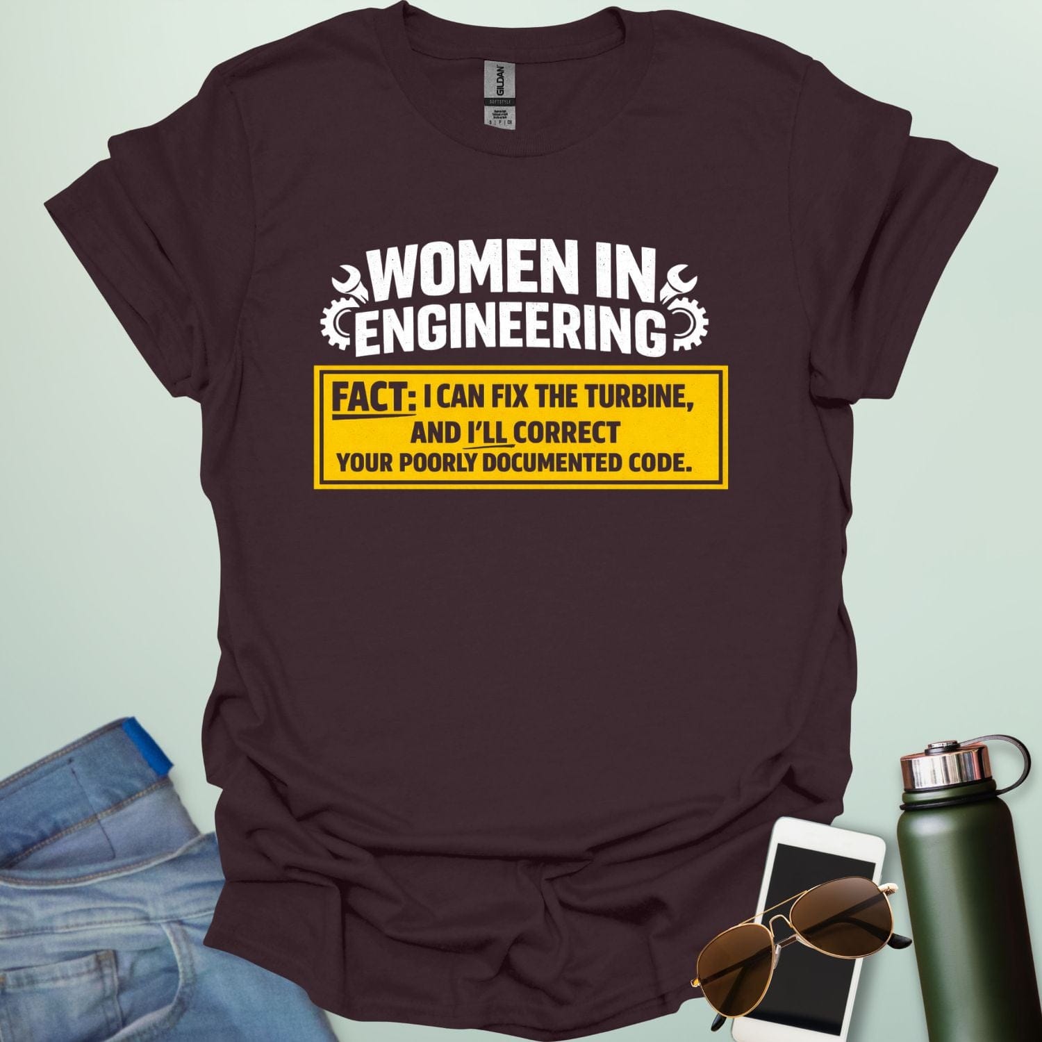 Graphic design featuring the text 'WOMEN IN ENGINEERING' with wrench and gear icons above a yellow box reading 'FACT: I CAN FIX THE TURBINE, AND I’LL CORRECT YOUR POORLY DOCUMENTED CODE.'