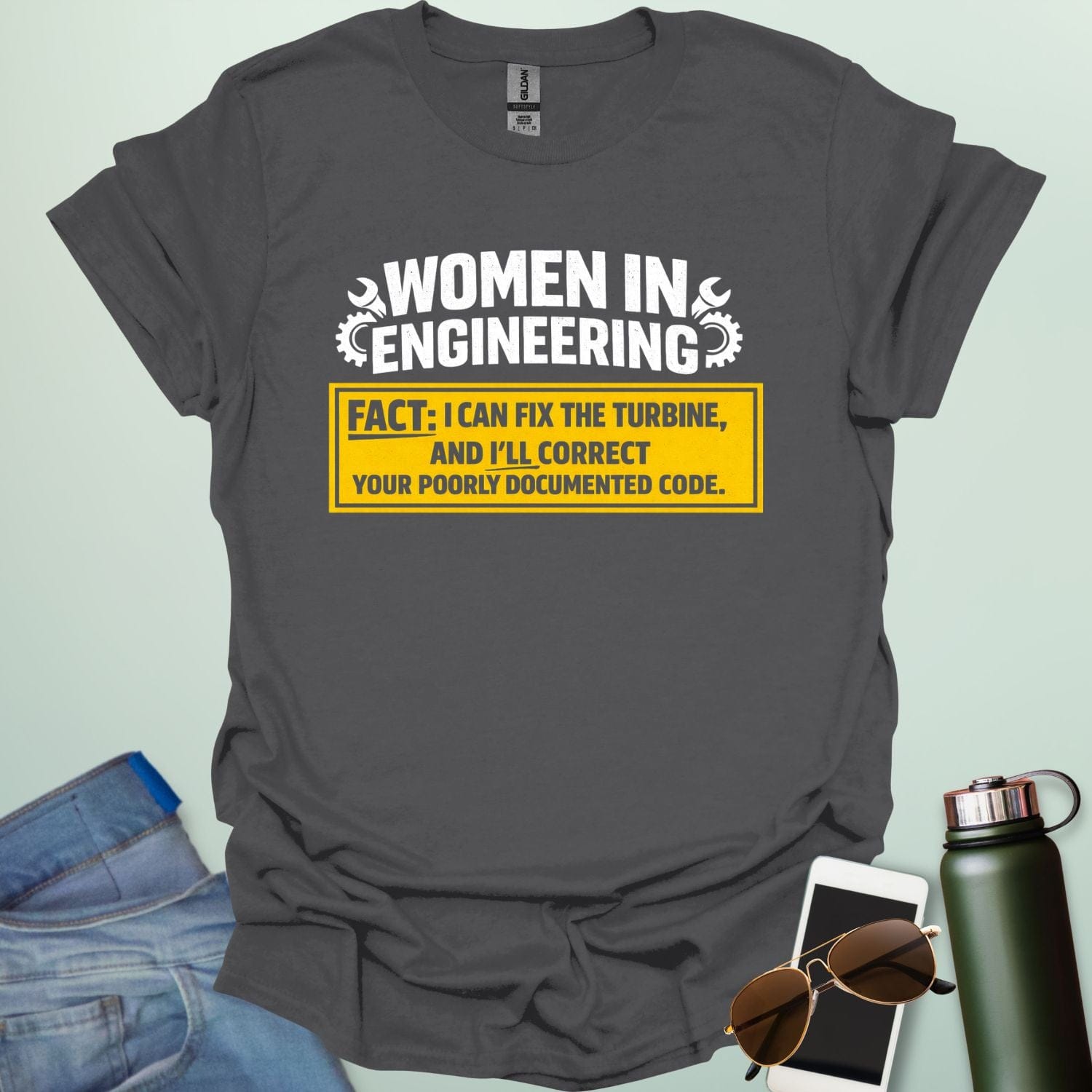 Graphic design featuring the text 'WOMEN IN ENGINEERING' with wrench and gear icons above a yellow box reading 'FACT: I CAN FIX THE TURBINE, AND I’LL CORRECT YOUR POORLY DOCUMENTED CODE.'
