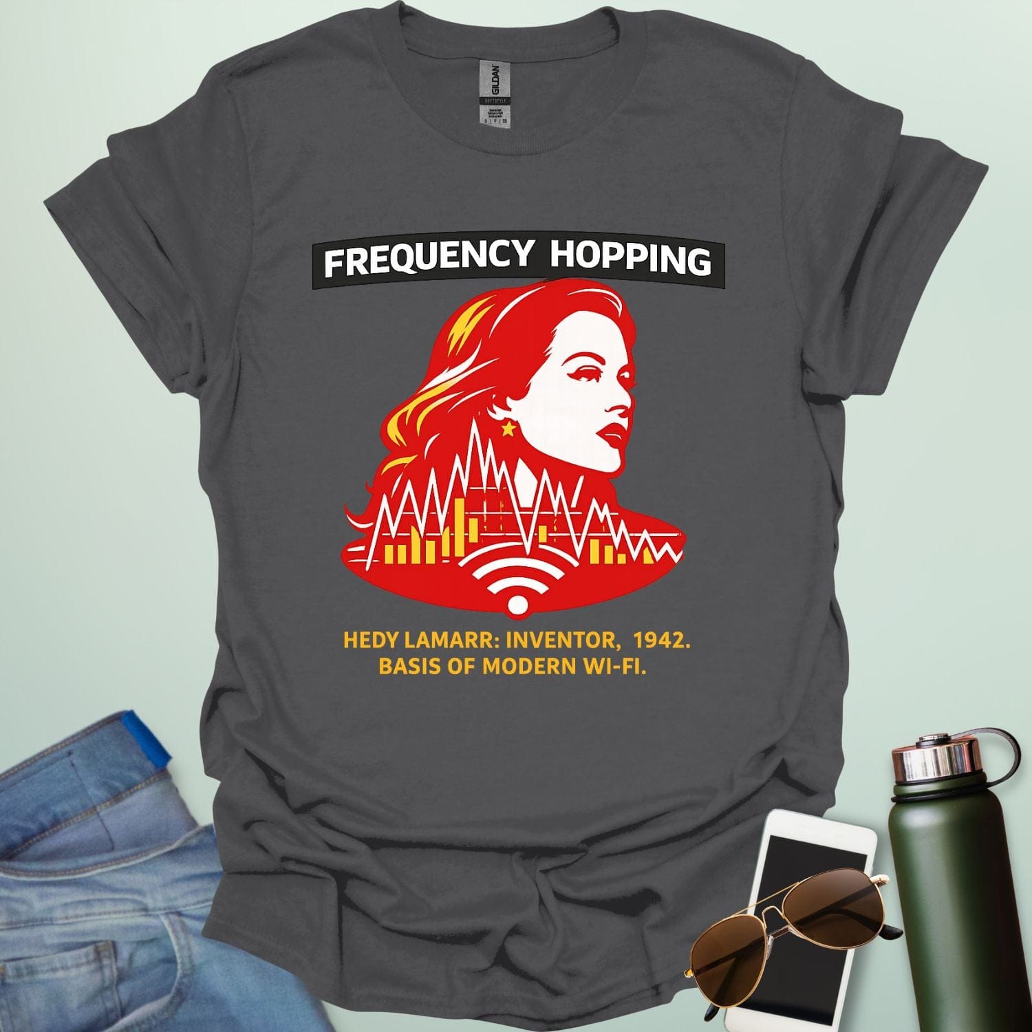Graphic design featuring a stylized red and yellow portrait of Hedy Lamarr with signal wave patterns, Wi-Fi icons, and text reading 'FREQUENCY HOPPING' and 'HEDY LAMARR: INVENTOR, 1942. BASIS OF MODERN WI-FI.'