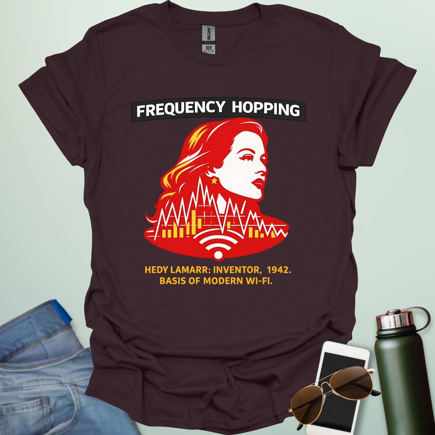 Graphic design featuring a stylized red and yellow portrait of Hedy Lamarr with signal wave patterns, Wi-Fi icons, and text reading 'FREQUENCY HOPPING' and 'HEDY LAMARR: INVENTOR, 1942. BASIS OF MODERN WI-FI.'