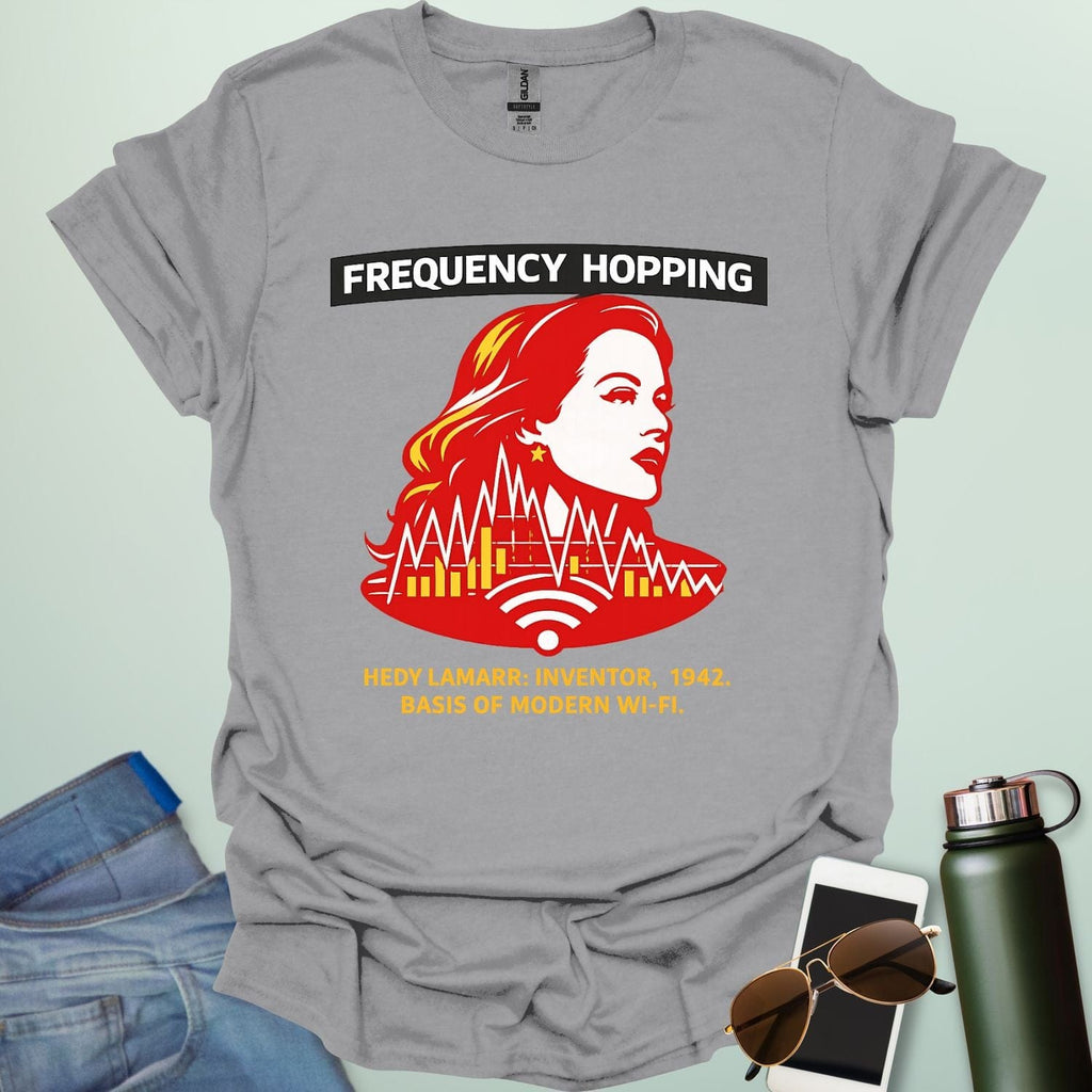 Graphic design featuring a stylized red and yellow portrait of Hedy Lamarr with signal wave patterns, Wi-Fi icons, and text reading 'FREQUENCY HOPPING' and 'HEDY LAMARR: INVENTOR, 1942. BASIS OF MODERN WI-FI.'