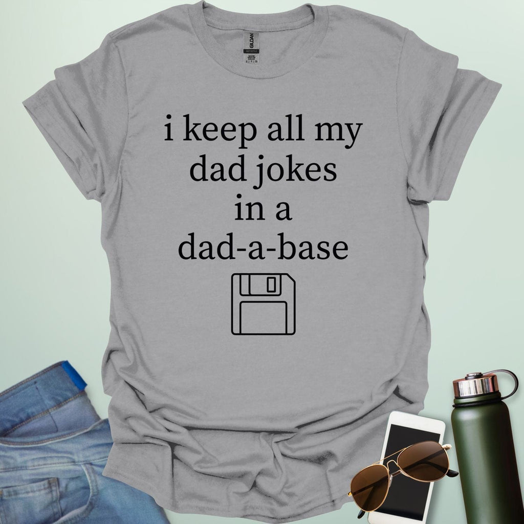 A graphic design featuring white text that reads "i keep all my dad jokes in a dad-a-base" above a minimalist white line art icon of a floppy disk.