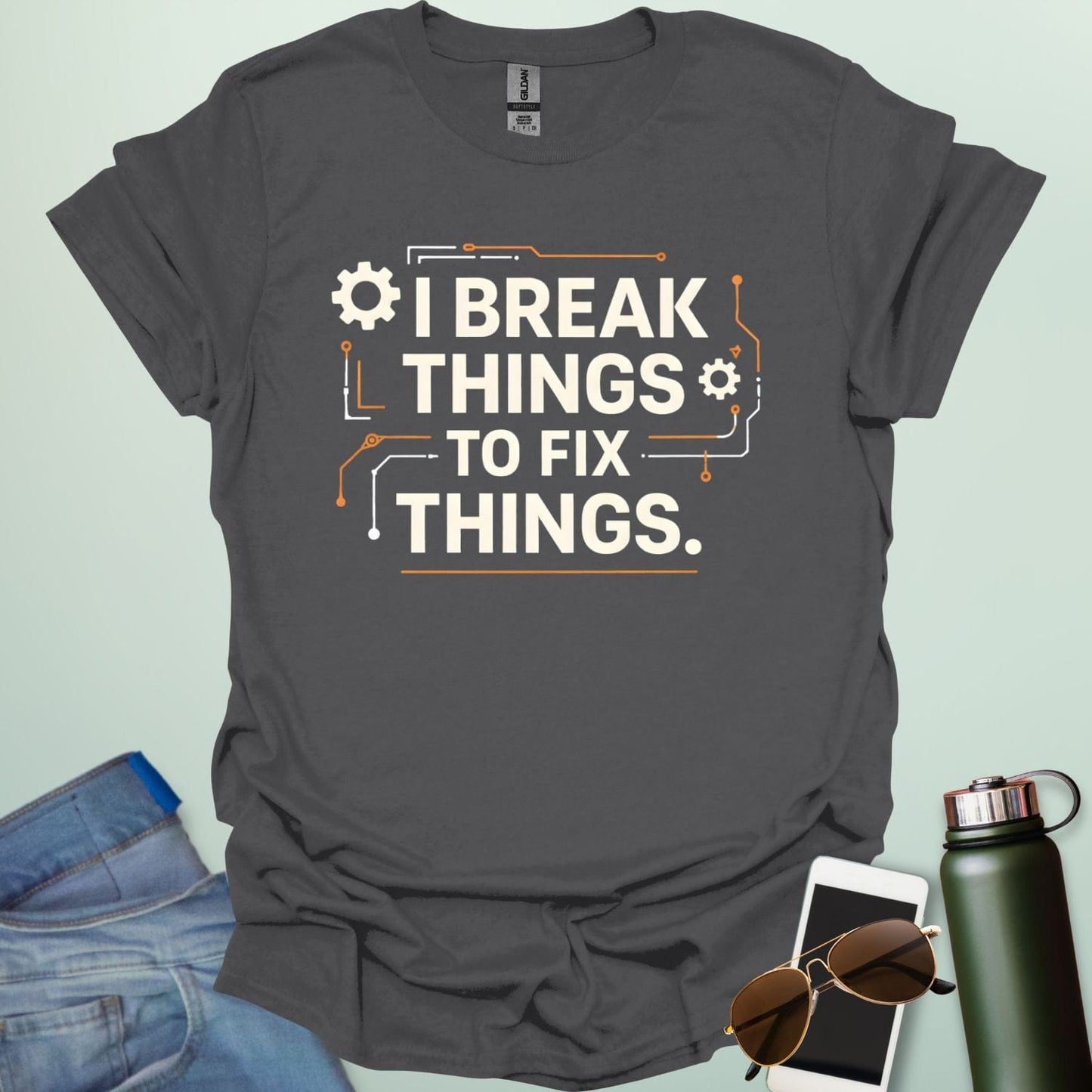 Graphic t-shirt design featuring bold text that reads 'I BREAK THINGS TO FIX THINGS' accented with mechanical gears and electronic circuit board line art.