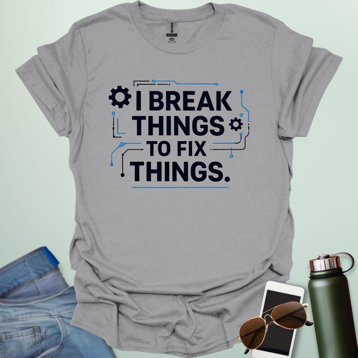 Graphic t-shirt design featuring bold text that reads 'I BREAK THINGS TO FIX THINGS' accented with mechanical gears and electronic circuit board line art.