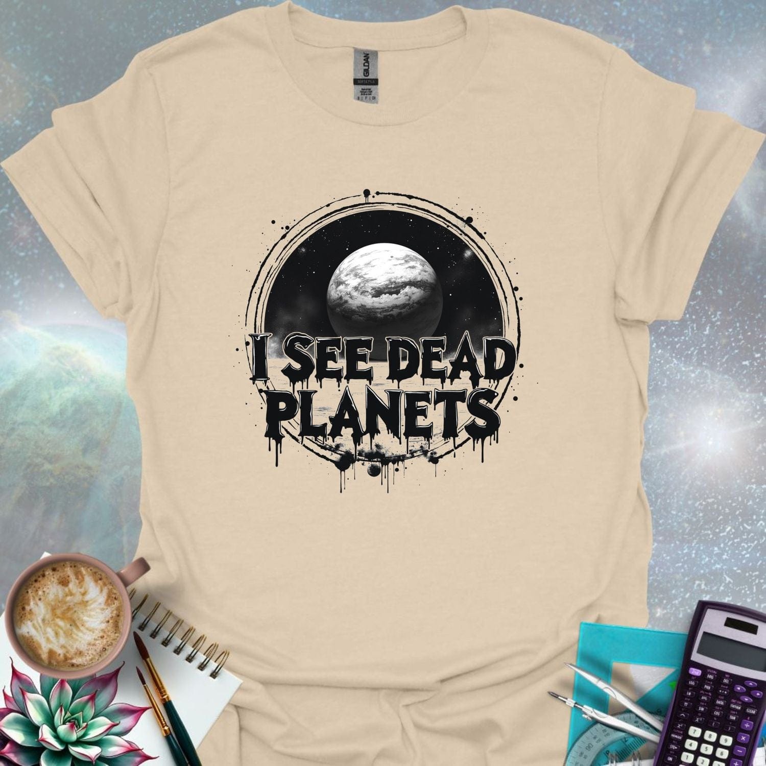T-shirt design featuring a planet with the text 'I See Dead Planets' in a distressed, gothic font, with splatters and a dark, space-themed background.