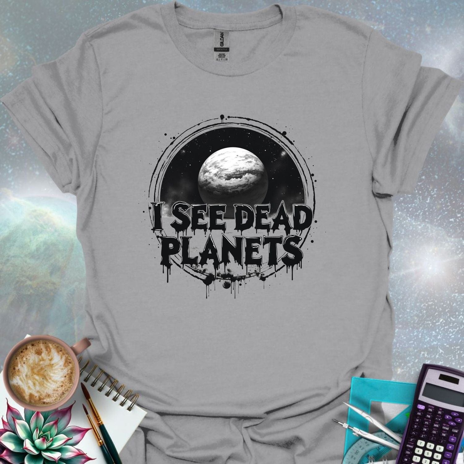 T-shirt design featuring a planet with the text 'I See Dead Planets' in a distressed, gothic font, with splatters and a dark, space-themed background.