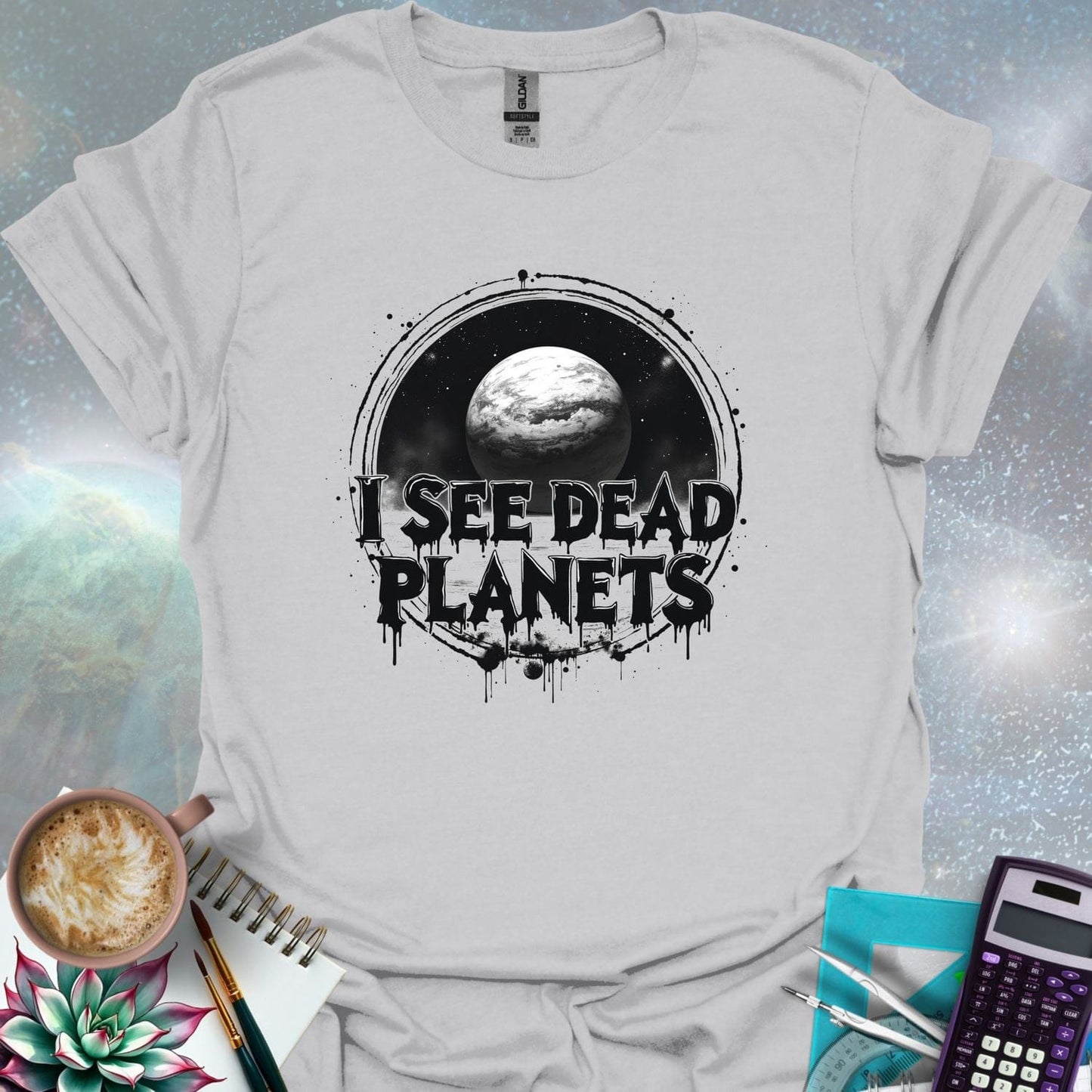 T-shirt design featuring a planet with the text 'I See Dead Planets' in a distressed, gothic font, with splatters and a dark, space-themed background.