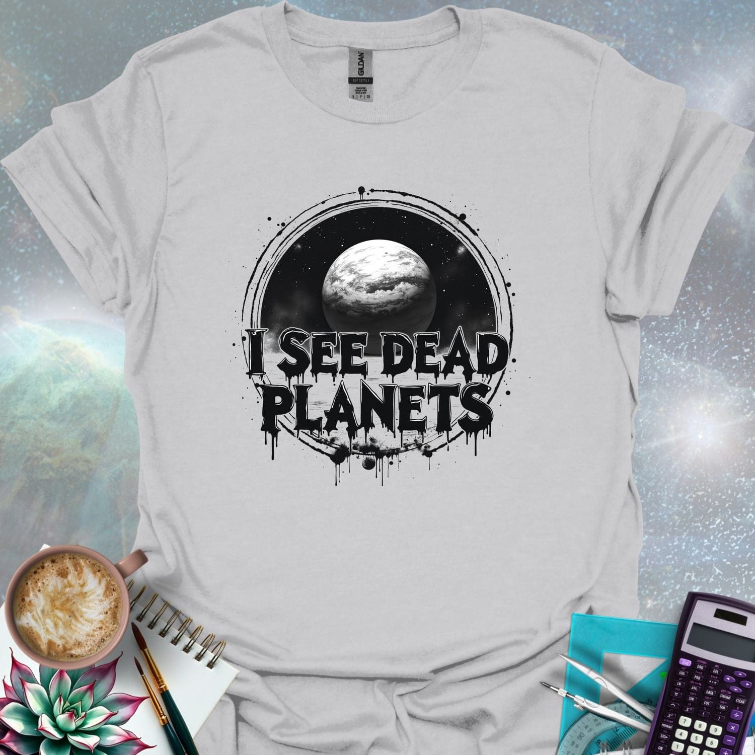 T-shirt design featuring a planet with the text 'I See Dead Planets' in a distressed, gothic font, with splatters and a dark, space-themed background.