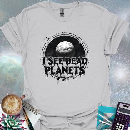 T-shirt design featuring a planet with the text 'I See Dead Planets' in a distressed, gothic font, with splatters and a dark, space-themed background.