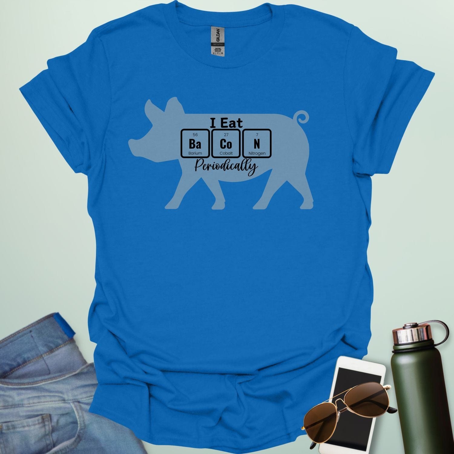 T-shirt design featuring a pig silhouette with the text 'I Eat Bacon Periodically,' where 'Bacon' is spelled using periodic table element symbols.