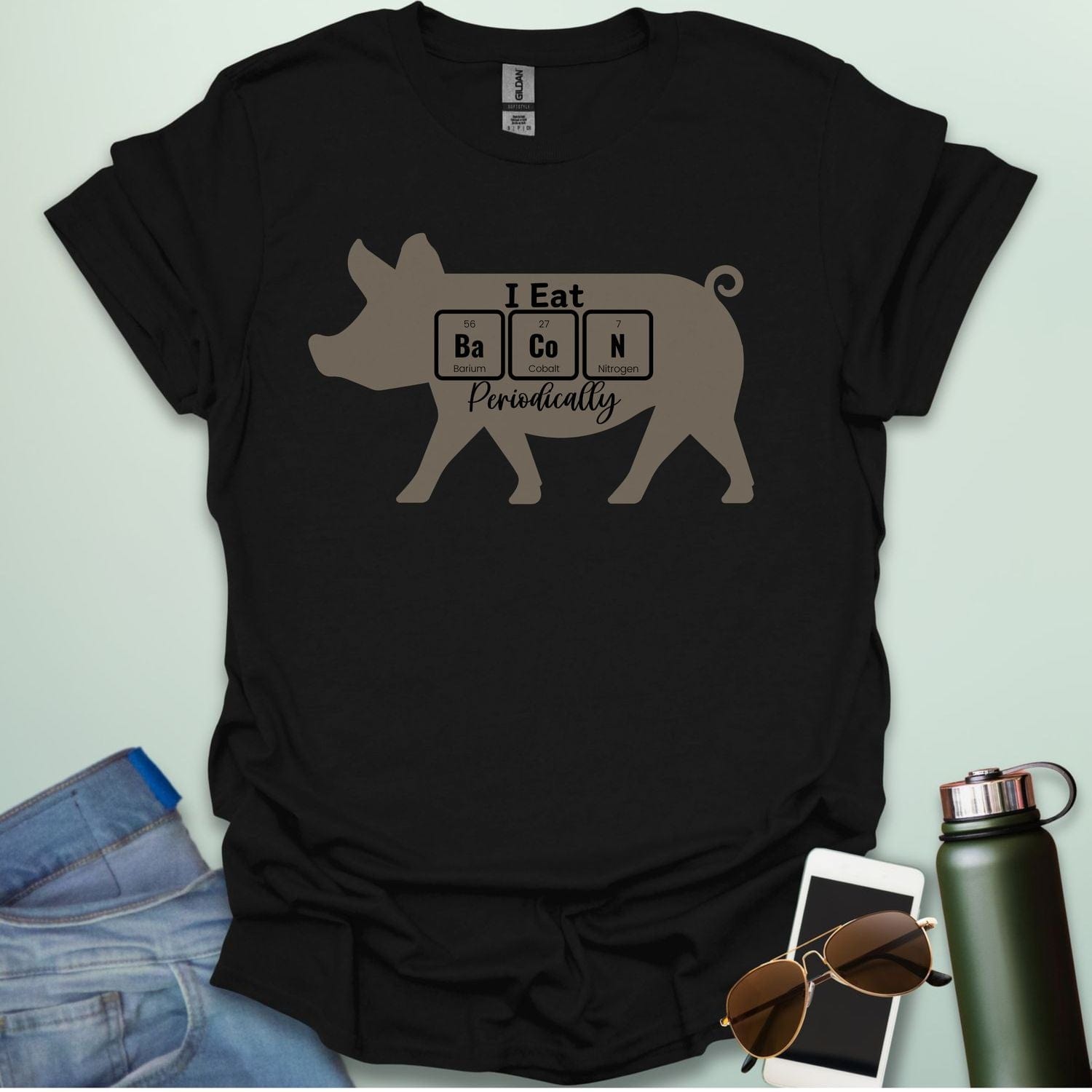 T-shirt design featuring a pig silhouette with the text 'I Eat Bacon Periodically,' where 'Bacon' is spelled using periodic table element symbols.
