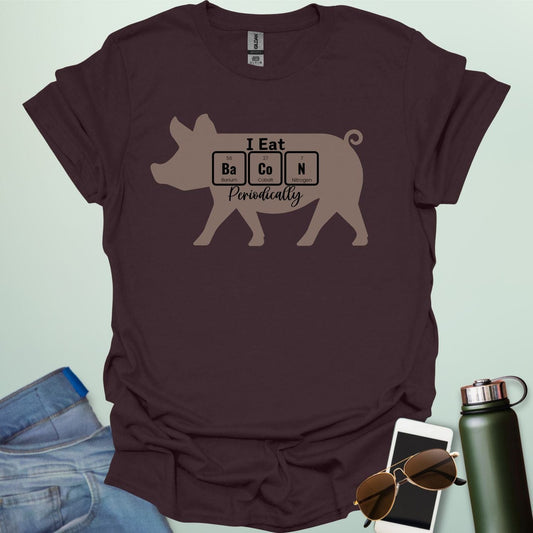 T-shirt design featuring a pig silhouette with the text 'I Eat Bacon Periodically,' where 'Bacon' is spelled using periodic table element symbols.