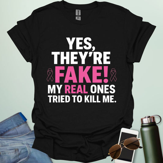 ‘Yes, They’re Fake — My Real Ones Tried to Kill Me’ t-shirt design with bold typography — breast cancer awareness & survivorship statement shirt.
