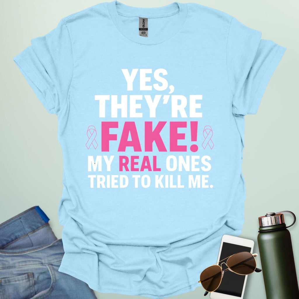 ‘Yes, They’re Fake — My Real Ones Tried to Kill Me’ t-shirt design with bold typography — breast cancer awareness & survivorship statement shirt.