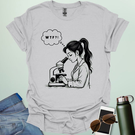 A funny t-shirt for scientists with a line drawing of a woman looking through a microscope and a thought bubble with the text 'WTF?!'