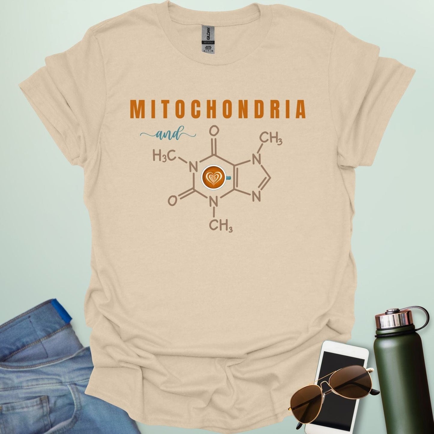 A tan t-shirt with the text 'MITOCHONDRIA and' above a graphic of the caffeine chemical structure with a coffee cup icon.