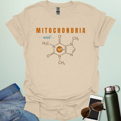 A tan t-shirt with the text 'MITOCHONDRIA and' above a graphic of the caffeine chemical structure with a coffee cup icon.
