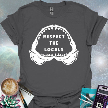 The silhouette of a menacing open shark jaw with sharp teeth, framing the text 'RESPECT THE LOCALS' in the center.