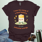 A cute cartoon graphic of a tired battery character sitting on a patch of grass with lightning bolts, atoms, and the text "I have the energy of a dead battery. It's still potential energy."