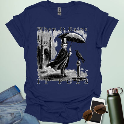 A literary pun t-shirt with a vintage illustration of Edgar Allan Poe holding an umbrella in the rain, next to a raven. The text reads 'When It Rains It Poes.'