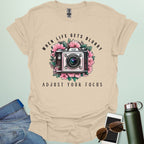 Vintage camera surrounded by flowers with the quote “When Life Gets Blurry, Adjust Your Focus.”
