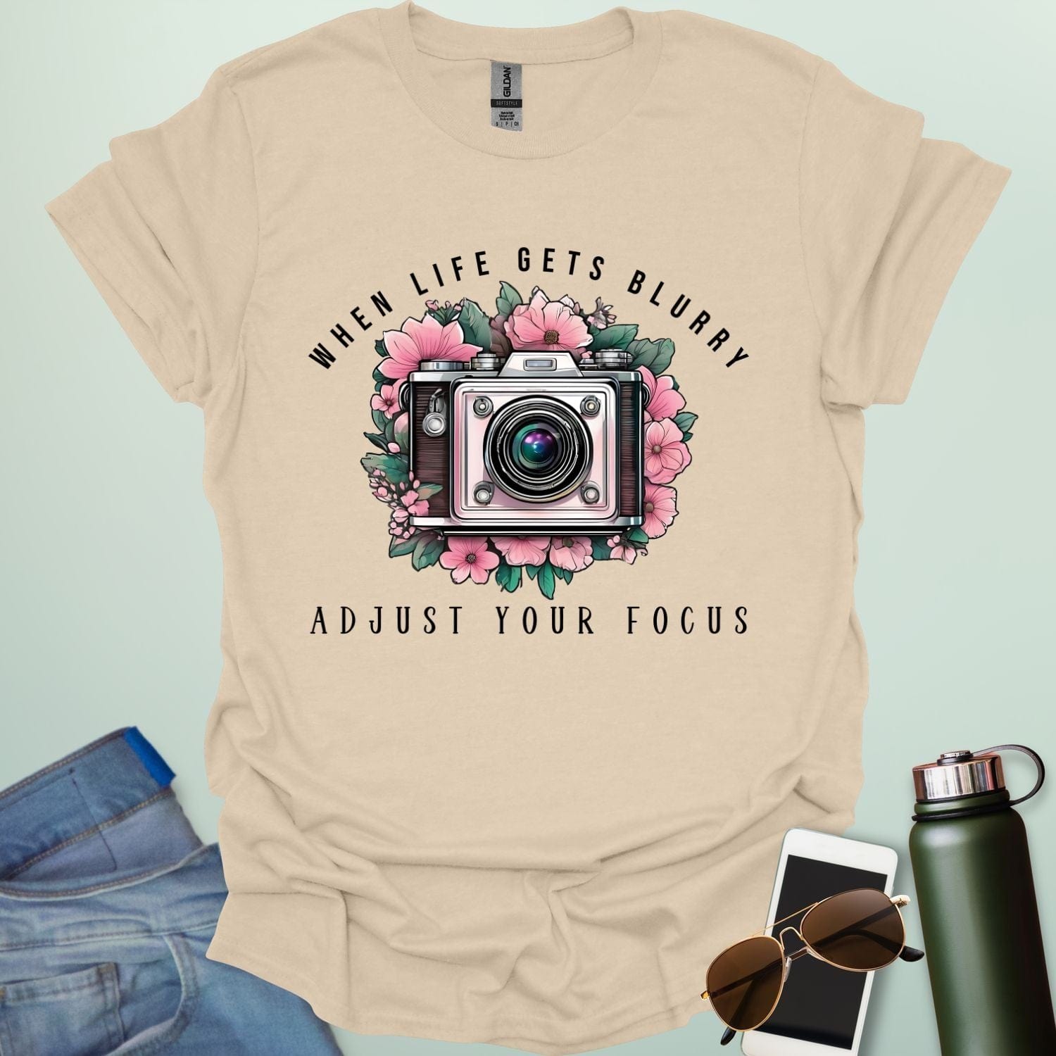 Vintage camera surrounded by flowers with the quote “When Life Gets Blurry, Adjust Your Focus.”